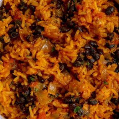 Bowl of black beans and rice garnished with cilantro and lime