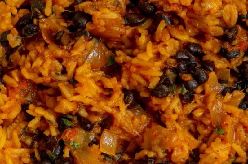 Bowl of black beans and rice garnished with cilantro and lime