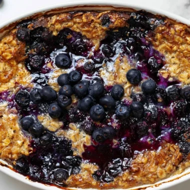 Delicious blueberry baked oatmeal in a dish, topped with fresh blueberries.