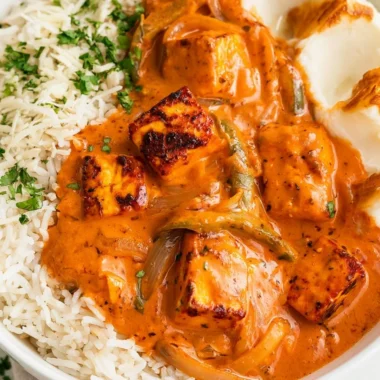 A delicious plate of Cottage Cheese Tikka Curry garnished with fresh herbs.