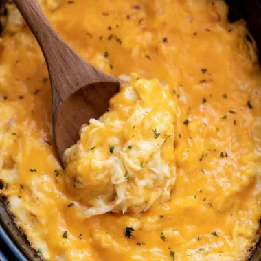 Delicious crockpot cheesy potatoes topped with melted cheese and herbs