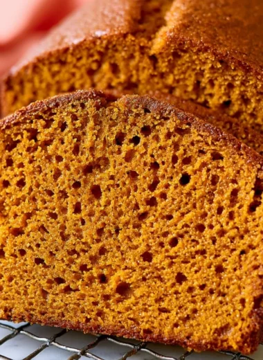 Slice of healthy pumpkin bread on a wooden table with autumn decorations.