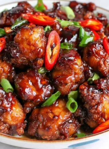Plate of Mongolian Chicken served with vegetables and rice in a flavorful sauce.