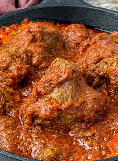 Bowl of Nigerian beef stew with vegetables and spices, showcasing rich flavors.