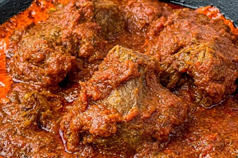 Bowl of Nigerian beef stew with vegetables and spices, showcasing rich flavors.