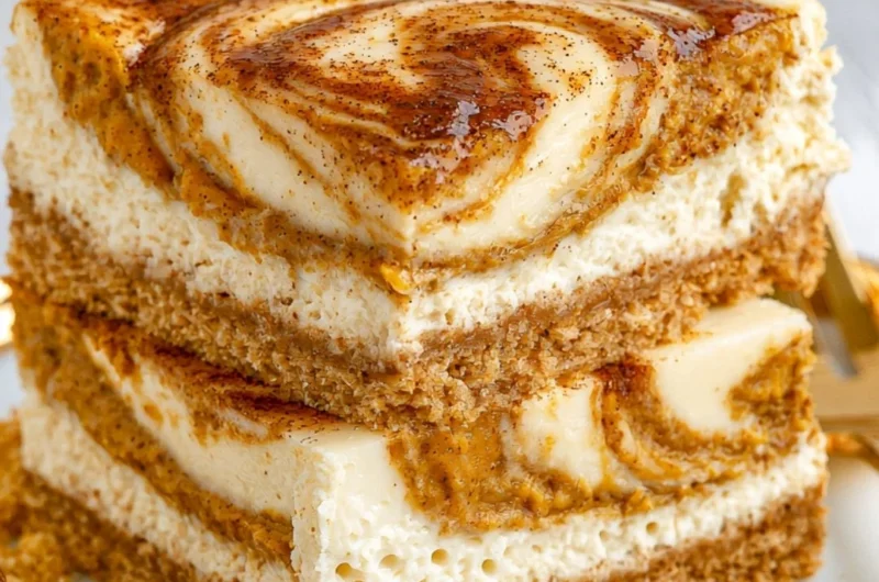 Delicious pumpkin cheesecake bars served on a rustic wooden table.