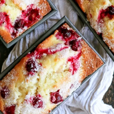 Freshly baked cranberry quick bread served on a wooden cutting board