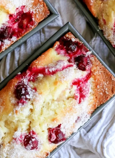 Freshly baked cranberry quick bread served on a wooden cutting board