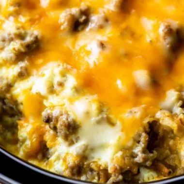 Cheesy sausage hashbrown breakfast plate with eggs and herbs