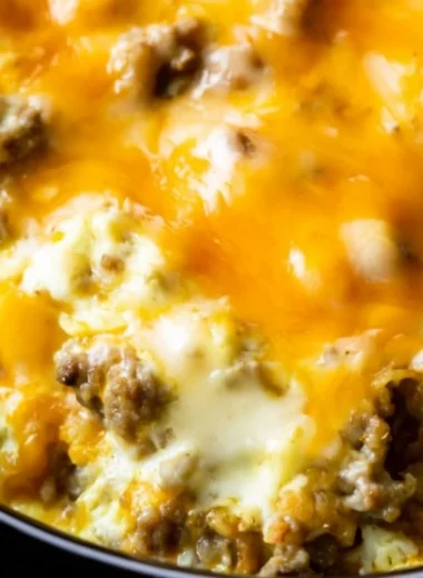 Cheesy sausage hashbrown breakfast plate with eggs and herbs