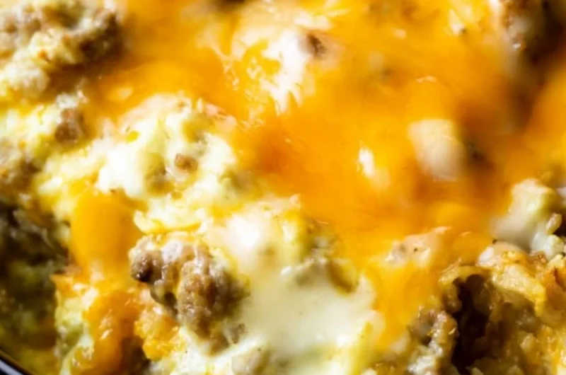 Cheesy sausage hashbrown breakfast plate with eggs and herbs