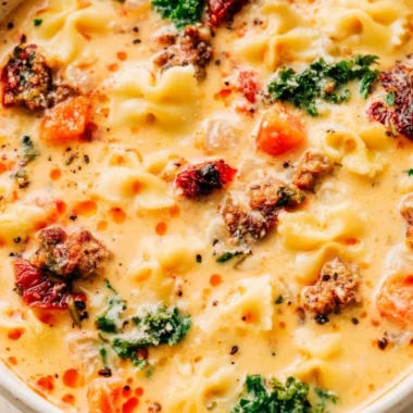 Delicious Italian sausage pasta soup in a bowl with fresh herbs and spices.