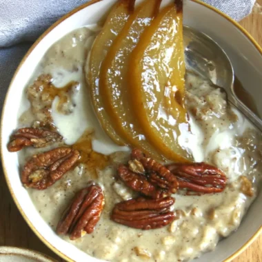Chai Spiced Pear Porridge topped with fresh spices and pears in a ceramic bowl
