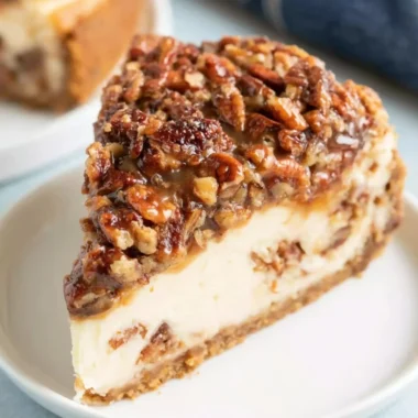 Delicious pecan pie cheesecake topped with pecans and caramel drizzle