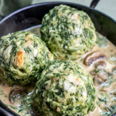 Spinach dumplings garnished with mushroom sauce on a plate.