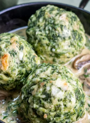 Spinach dumplings garnished with mushroom sauce on a plate.