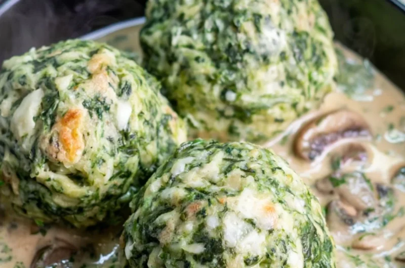 Spinach dumplings garnished with mushroom sauce on a plate.